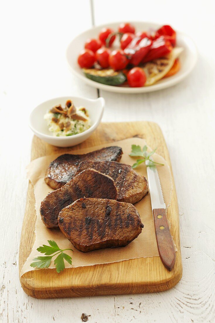 Grilled beefsteaks, garlic butter and tomato salad
