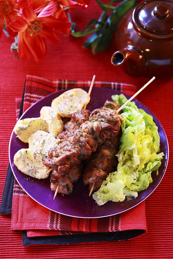 Meat kebabs with potatoes and lettuce