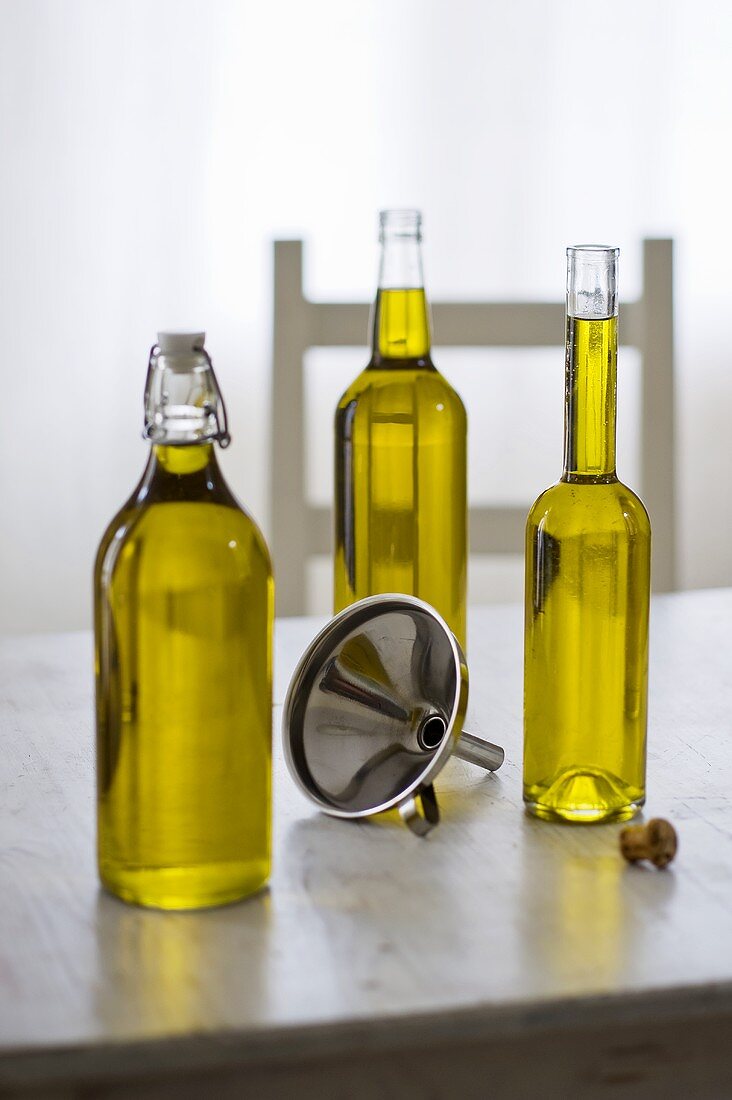 Three bottles of olive oil with funnel