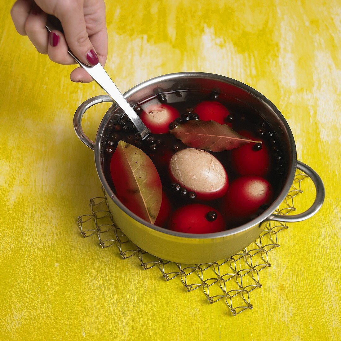 Putting eggs into red dyeing liquid (natural dyeing)