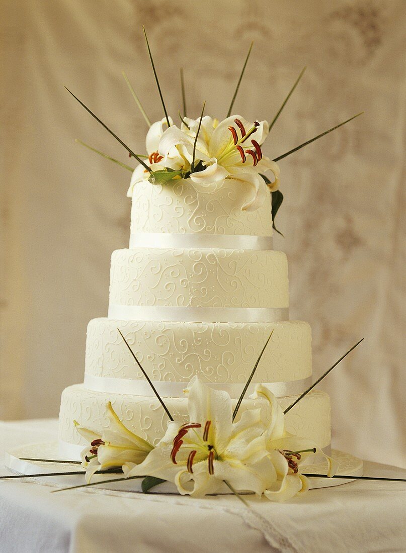 Decorated, four-tier wedding cake with lilies