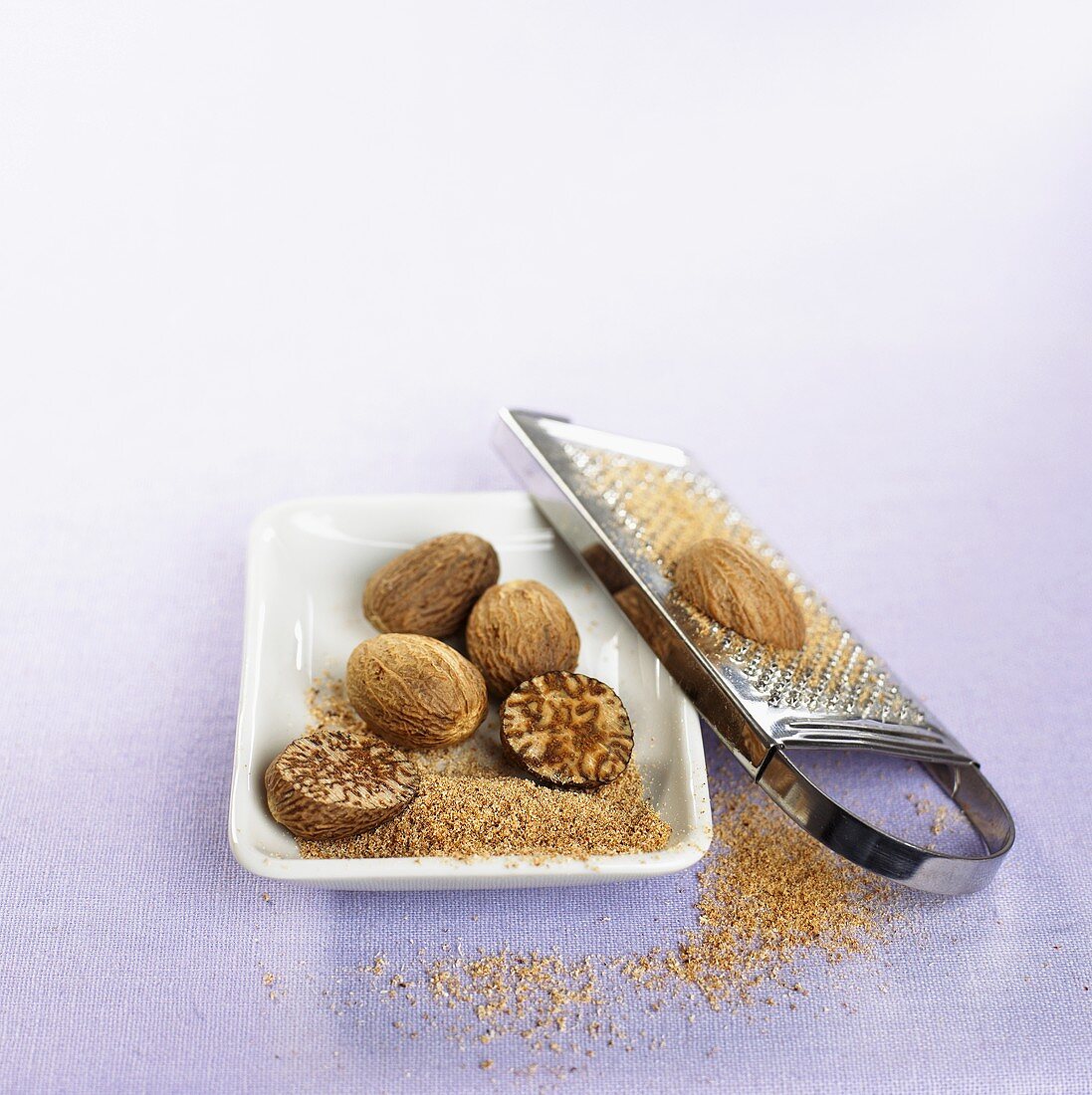 Grated nutmeg, whole nutmegs and grater