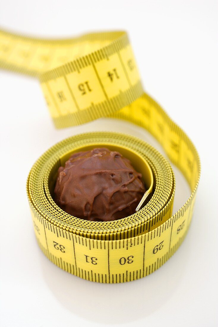 Chocolate truffle lying in rolled-up tape measure