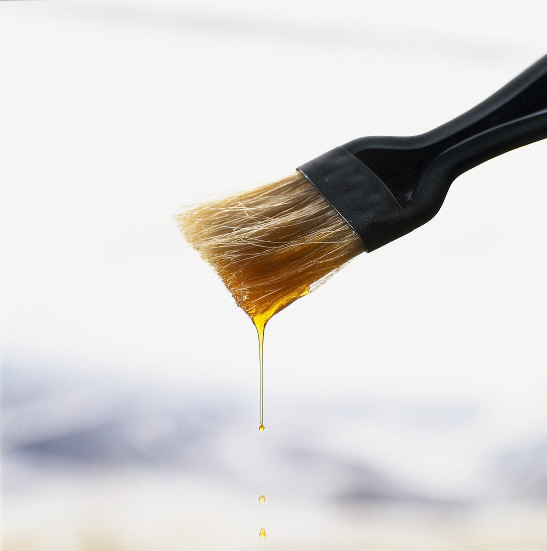 Olive oil dripping from a pastry brush