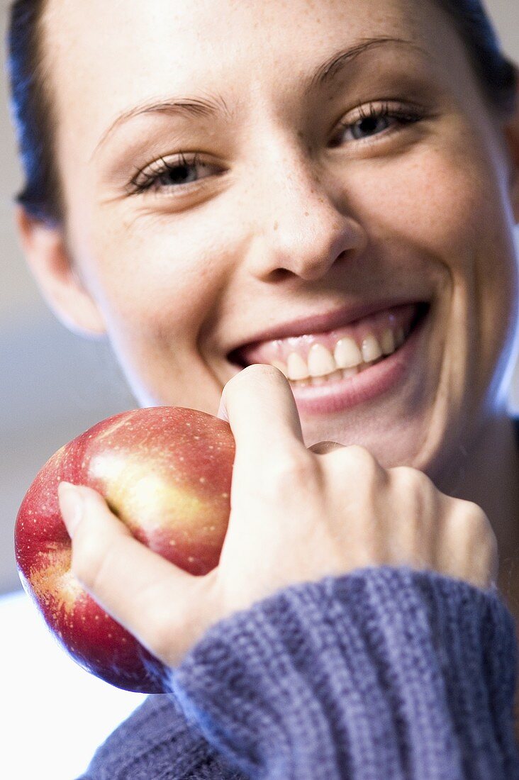 Lachende Frau hält einen Apfel