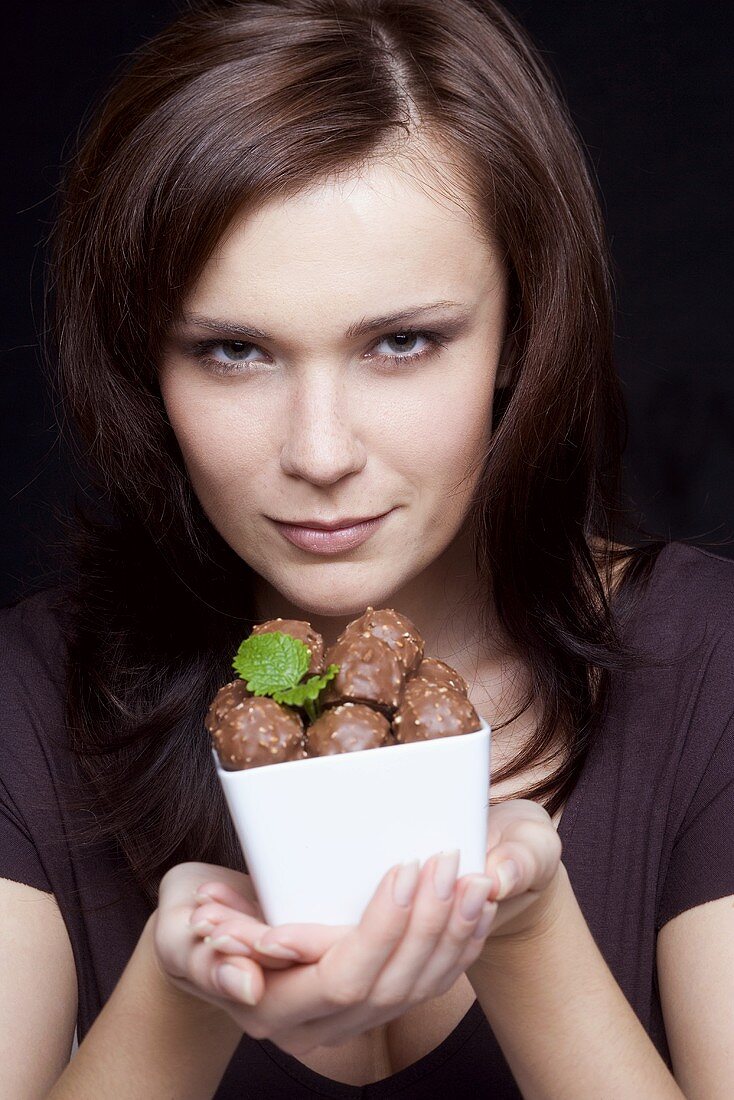 Young woman holding a bowl of chocolates