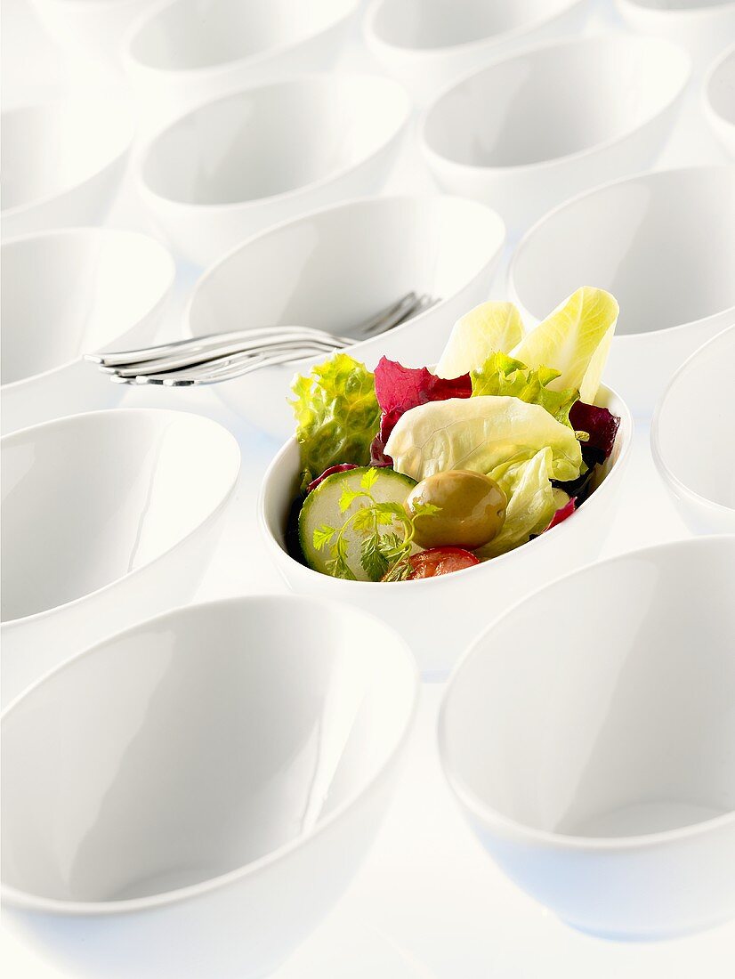 Lots of bowls, one filled with salad leaves