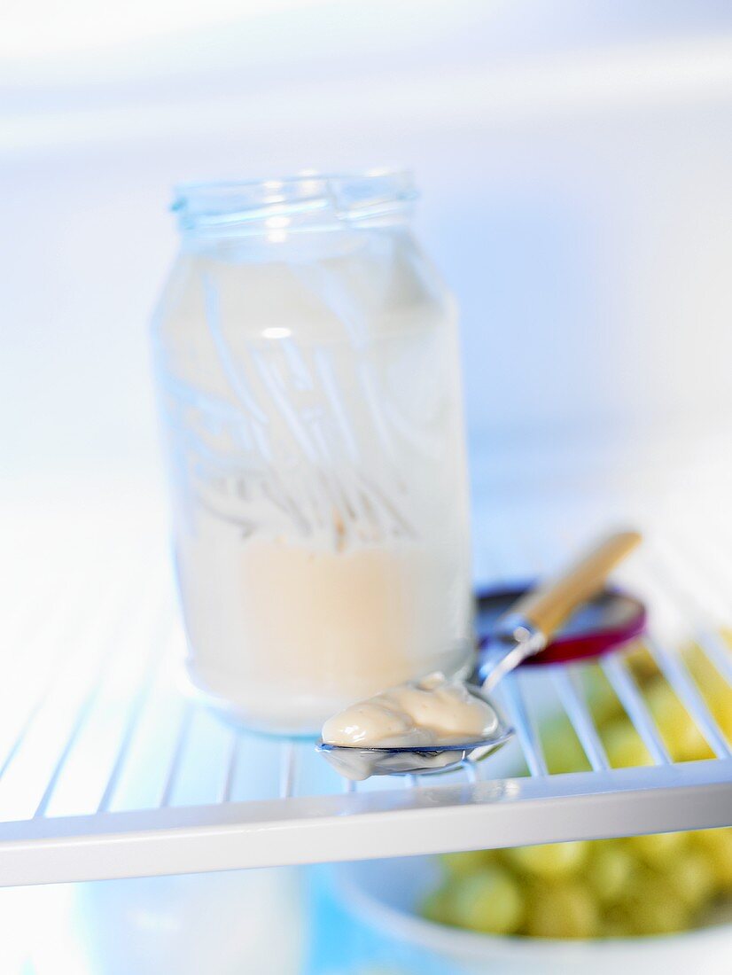 Mayonnaise on spoon beside a mayonnaise jar