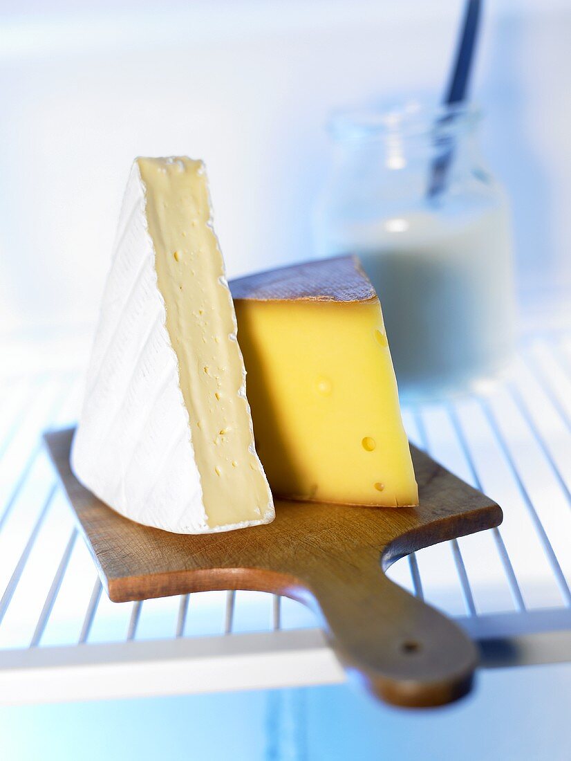 Pieces of cheese on a board in fridge