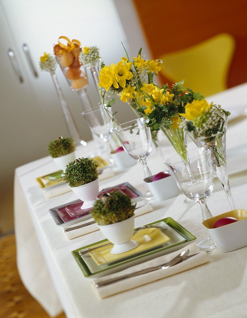 Table laid for Easter with pots of cress on plates