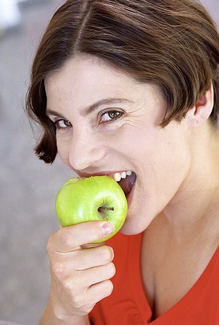 Junge Frau beisst in einen Apfel