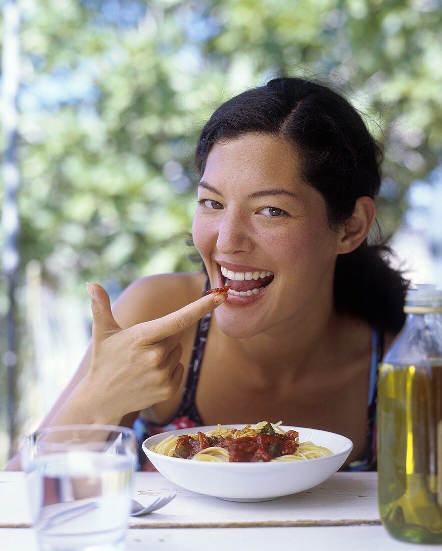 A woman with tomato sauce on her finger