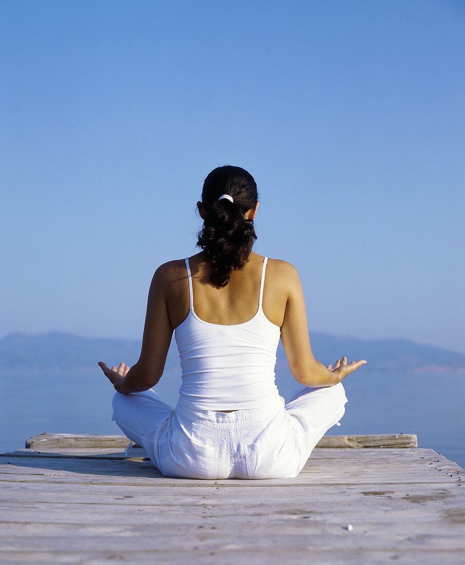 A woman meditating on a landing stage