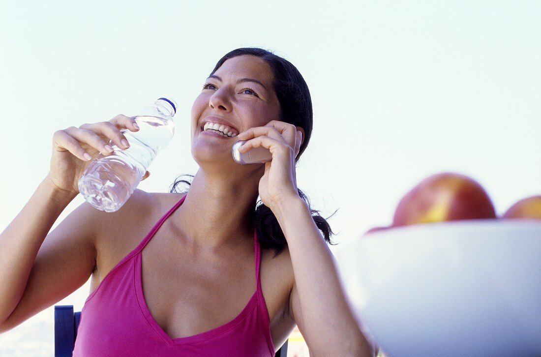 Junge Frau mit Handy und Wasserflasche