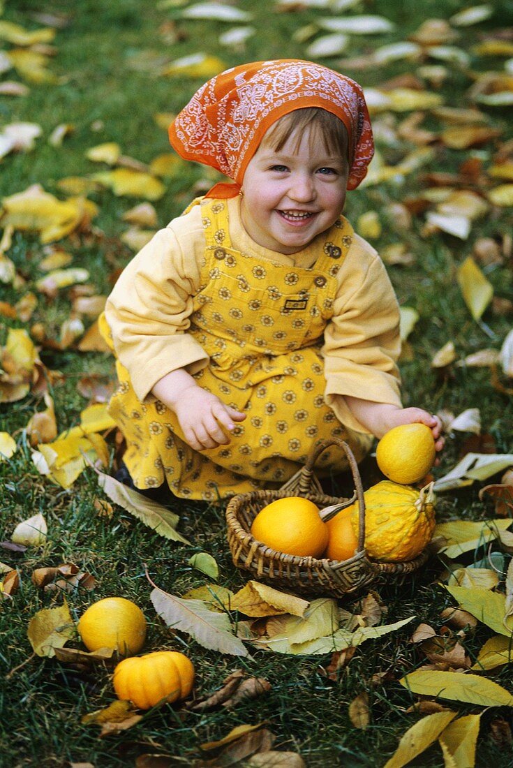 Kleines lachendes Mädchen mit Minikürbissen