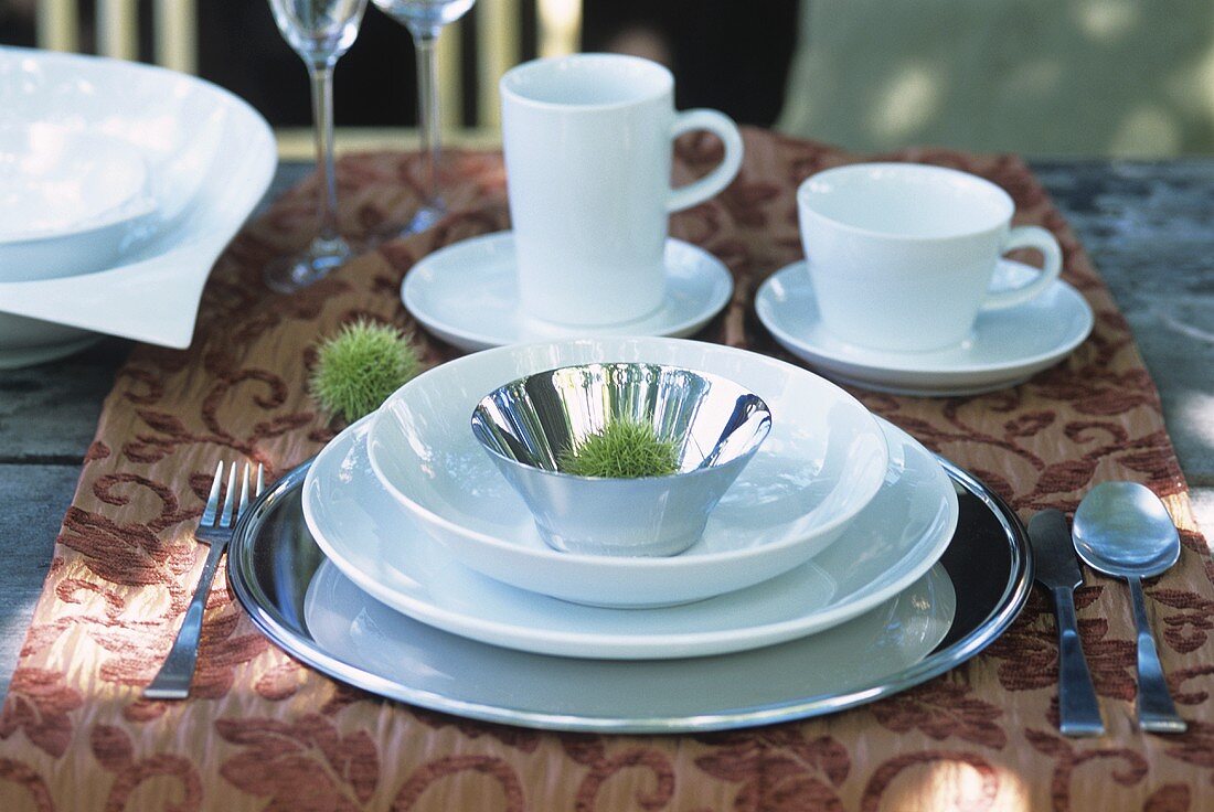 Place-setting with white tableware on a garden table