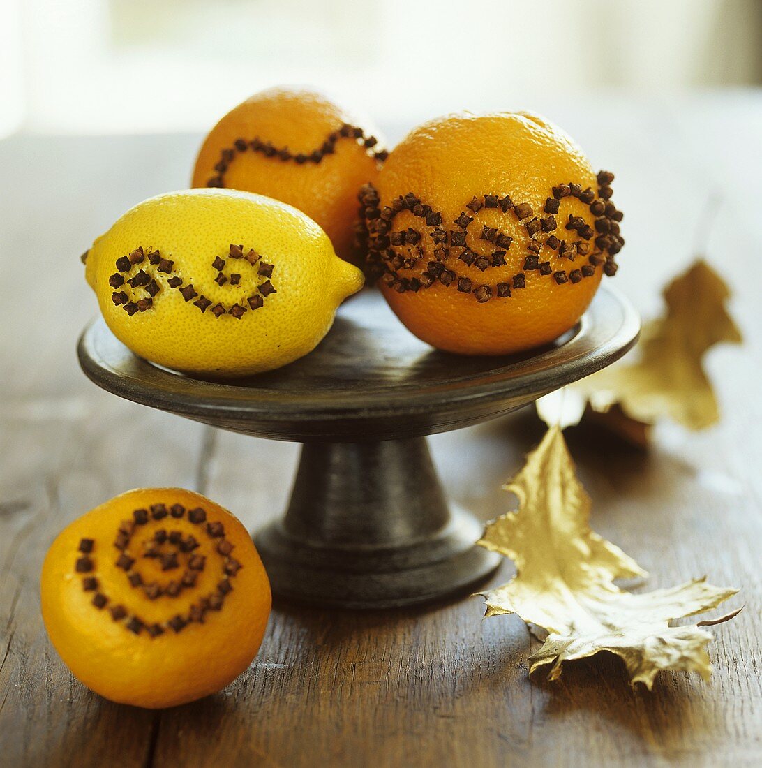 Mit Nelken gespickte Orangen und Zitrone in einer Schale