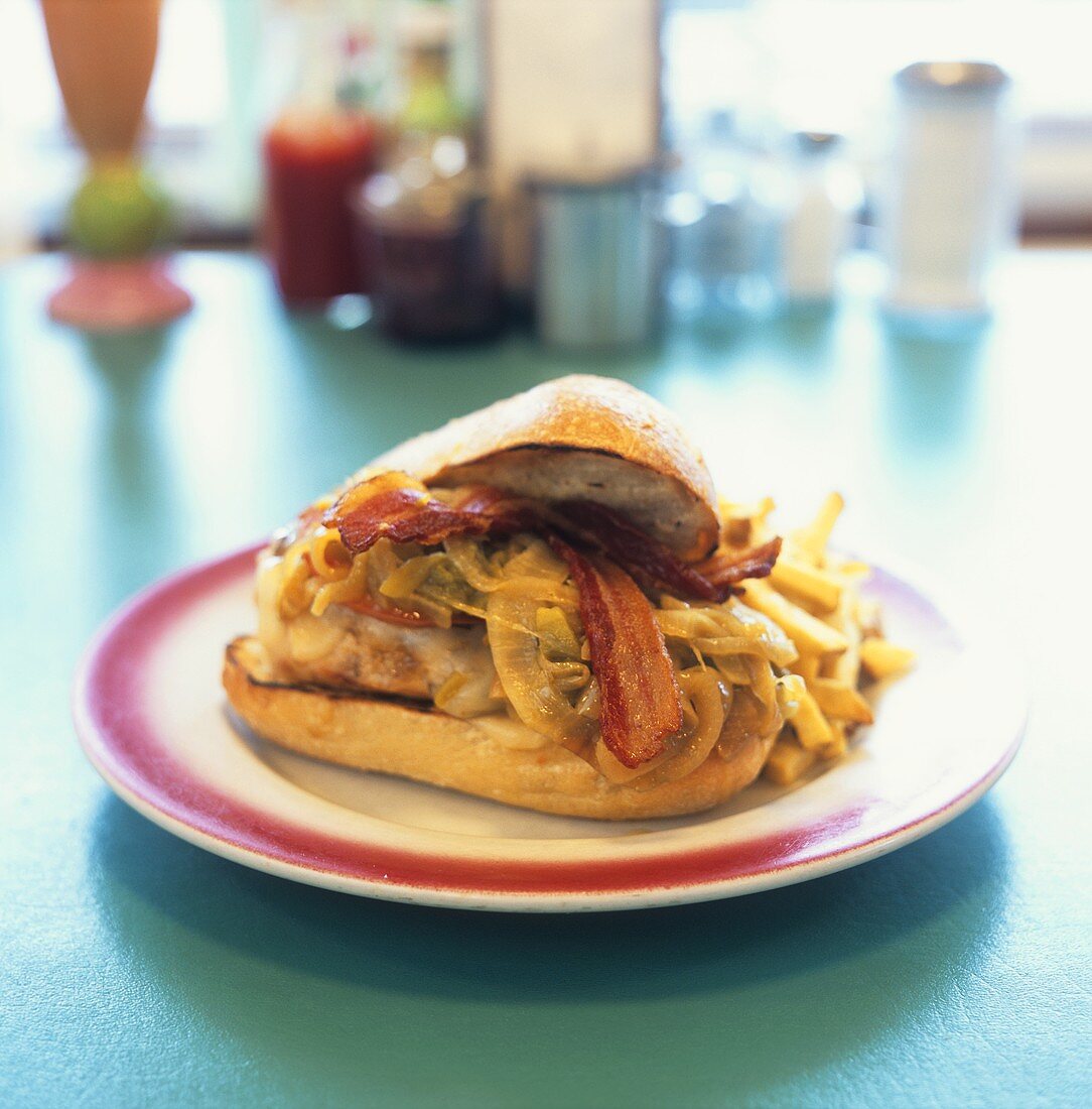 Chicken breast, bacon & onions in a sandwich, with chips