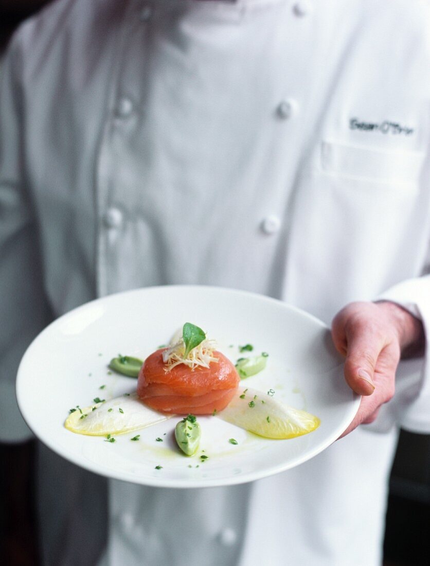 Head chef holding salmon in shape of timbale on a plate