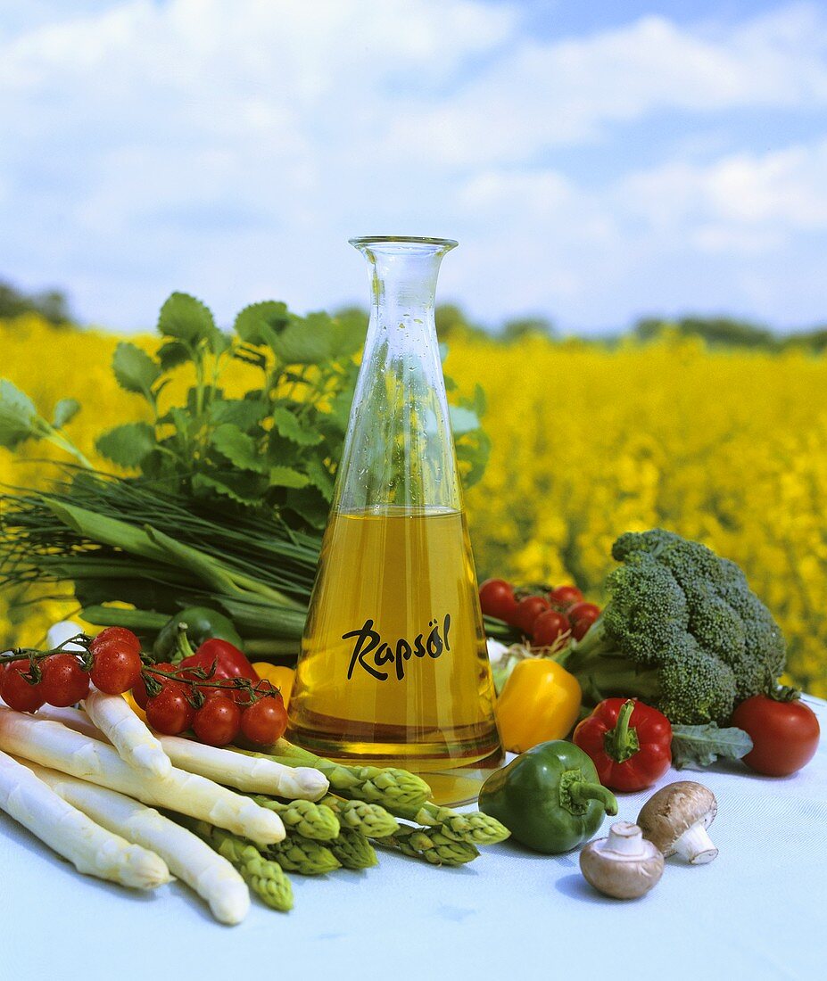 Rape seed oil with fresh vegetables in front of rape field