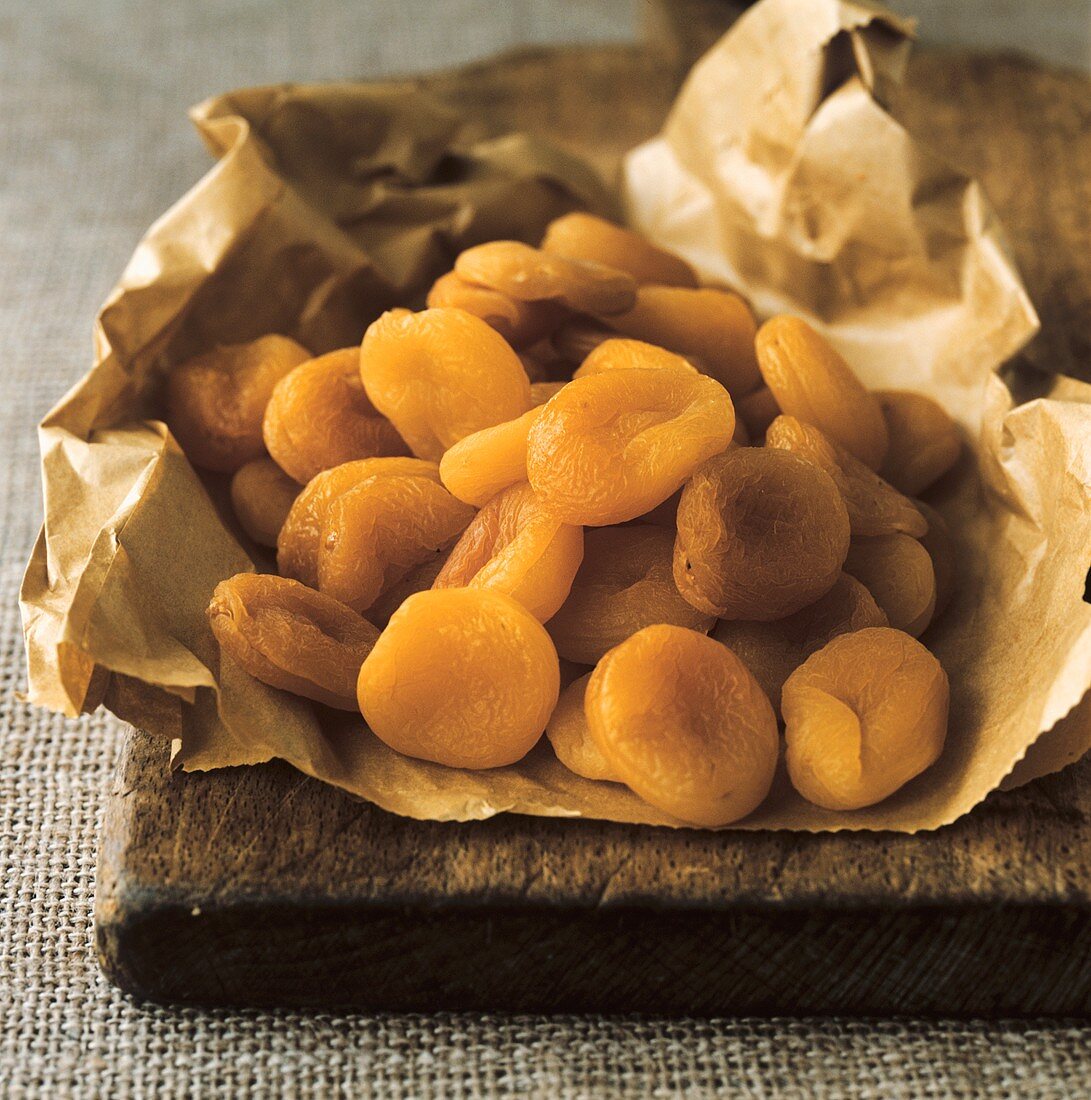 Dried apricots in packaging on a wooden board