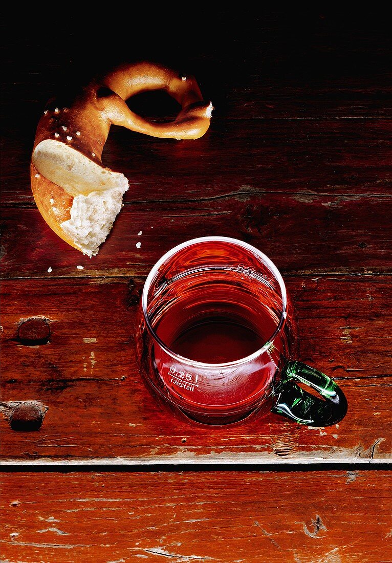 Rotwein im Henkelglas und eine halb gegessene Laugenbrezel