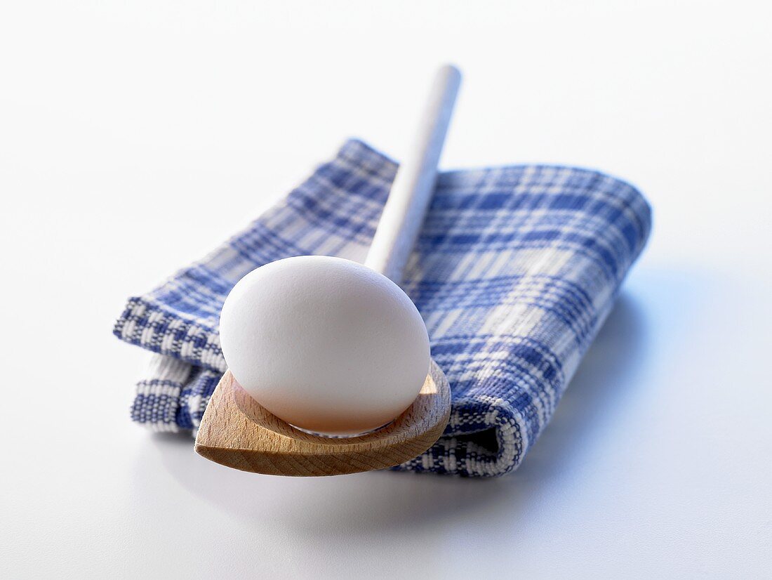 A white egg on a wooden spoon