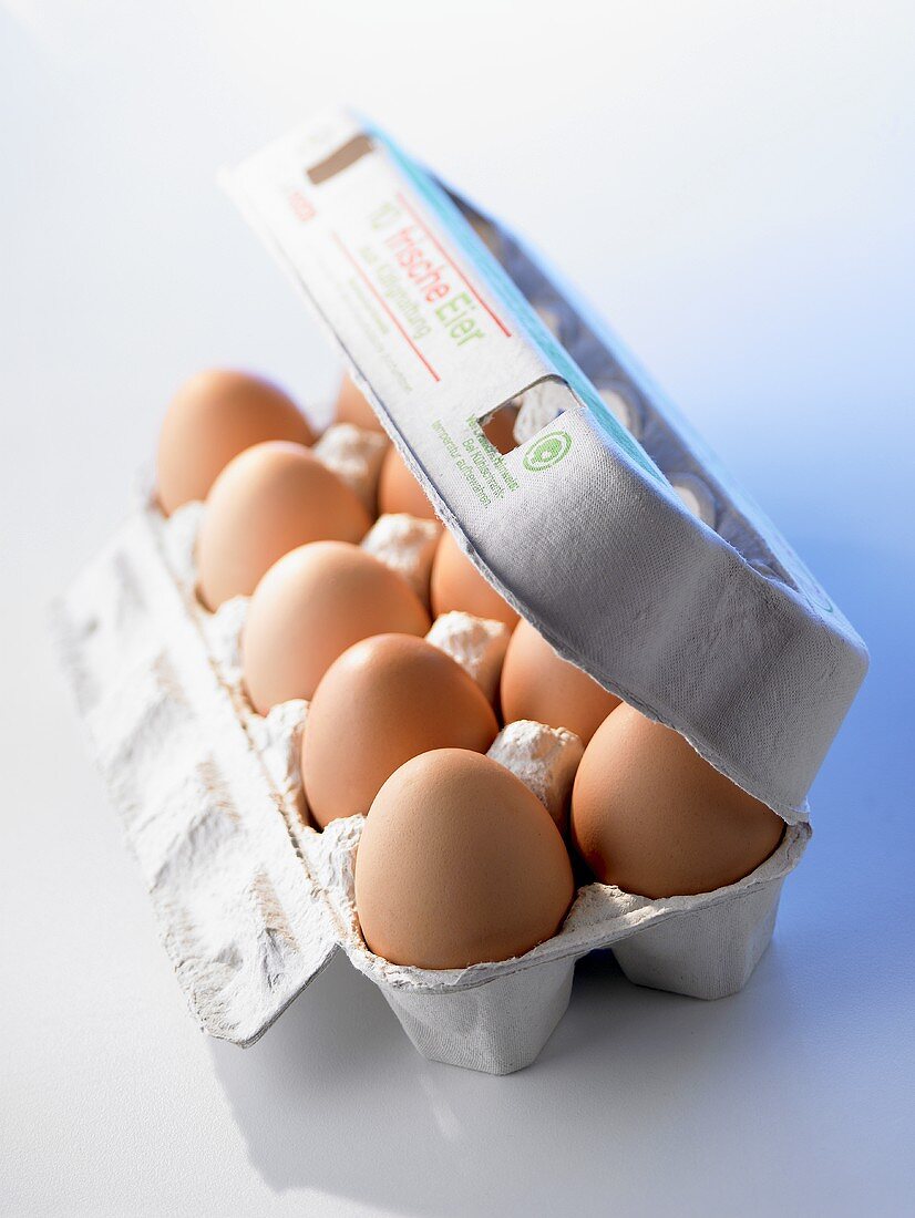 Ten brown eggs in half-opened egg box
