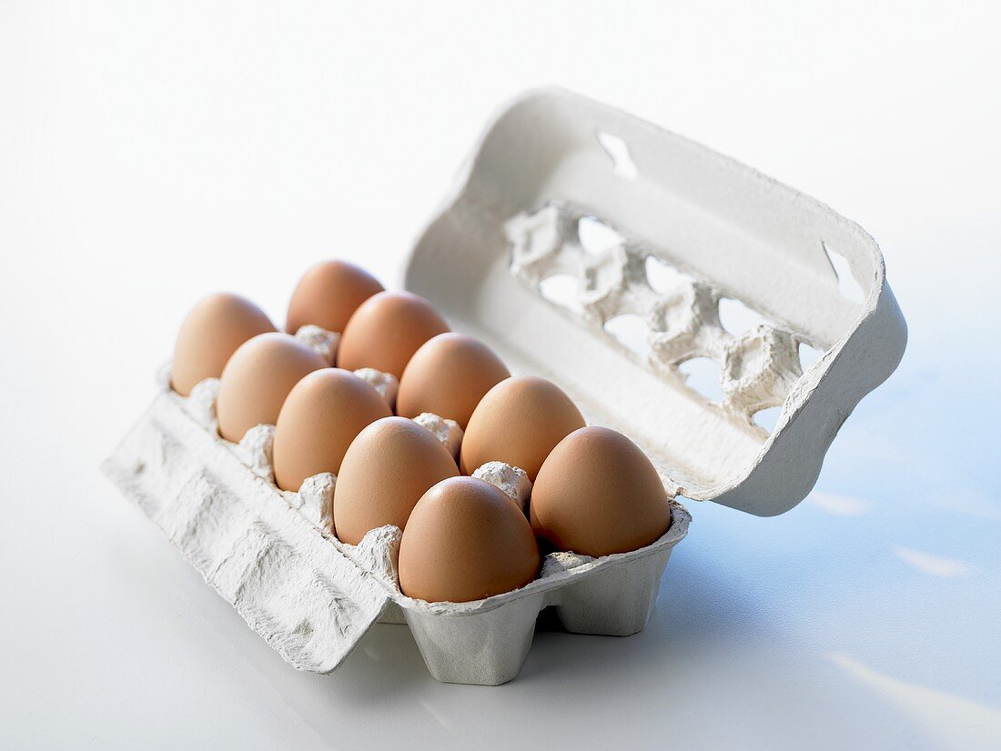Ten brown eggs in open egg box