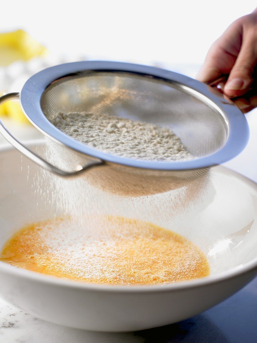 Sieving flour into beaten eggs