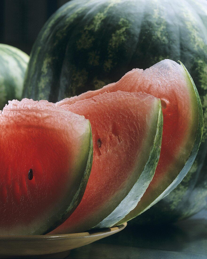 Slices of watermelon in front of a watermelon