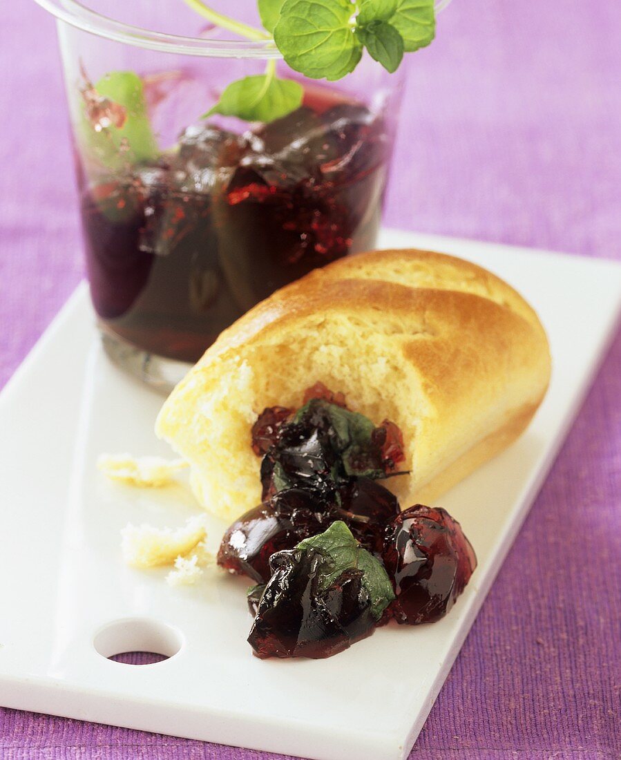 Raspberry and redcurrant jelly on a board with bread roll