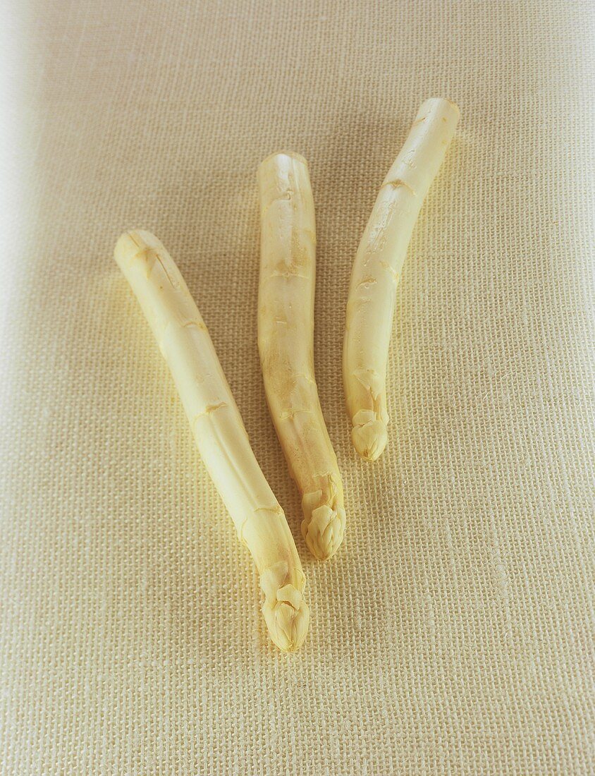 Three spears of white asparagus on linen