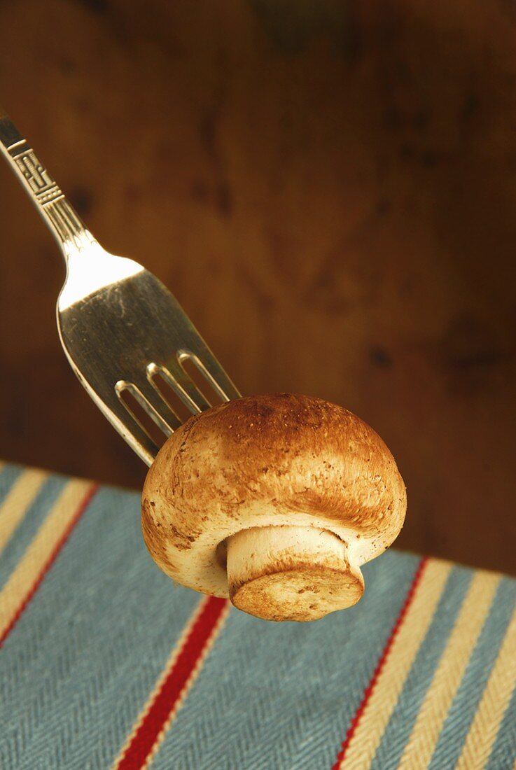 Fresh button mushroom on a fork