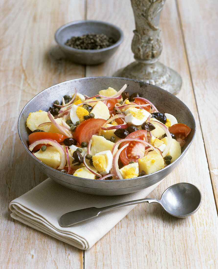 Potato salad with tomatoes, onions, egg, olives and capers