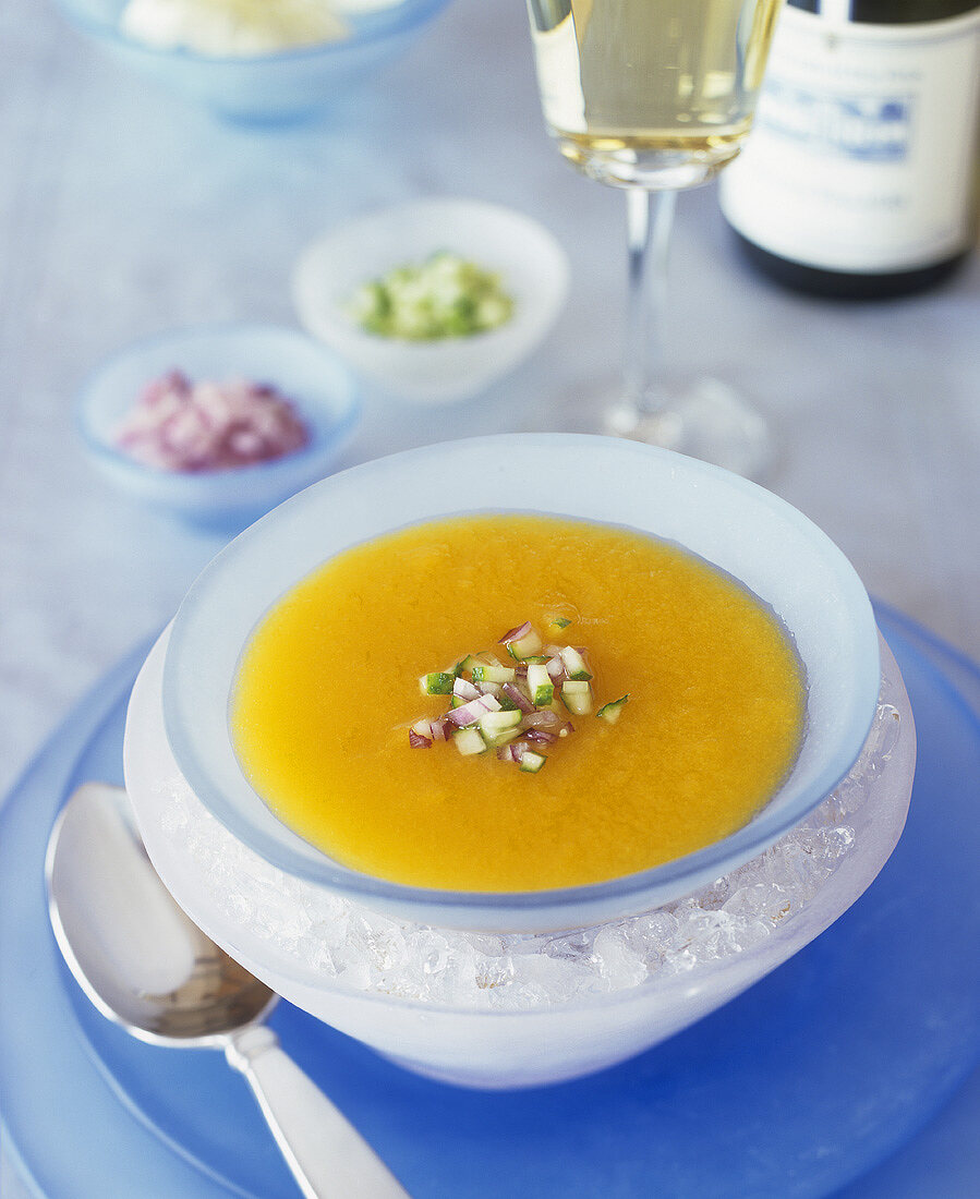 Chilled carrot cream soup with diced cucumber and onion