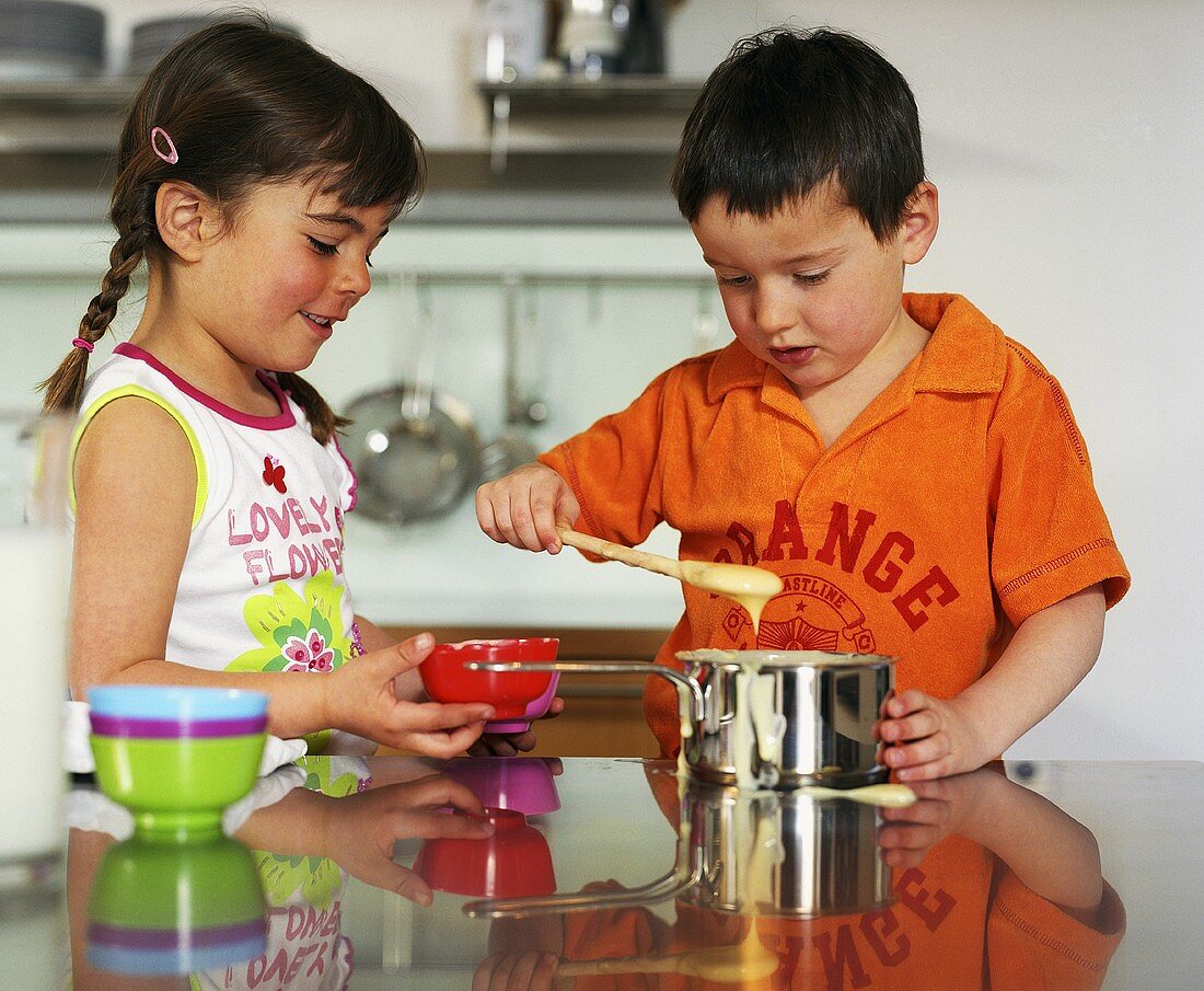 Zwei Kinder beim Pudding Kochen