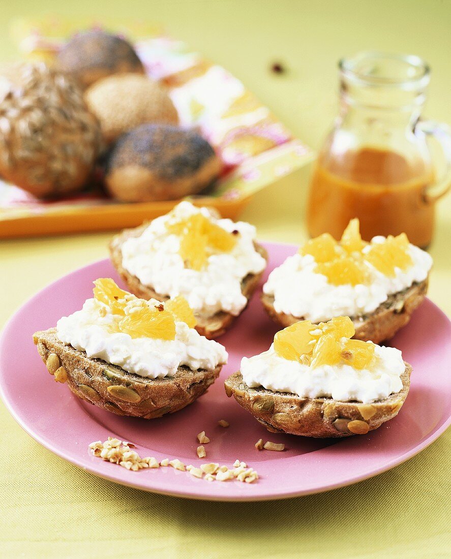 Bread rolls topped with soft cheese and orange