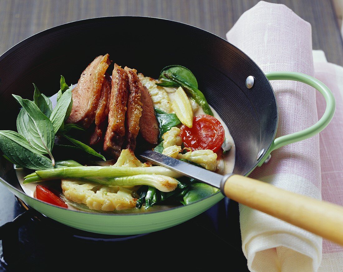 Vegetable curry with roasted duck breast & Thai basil in wok