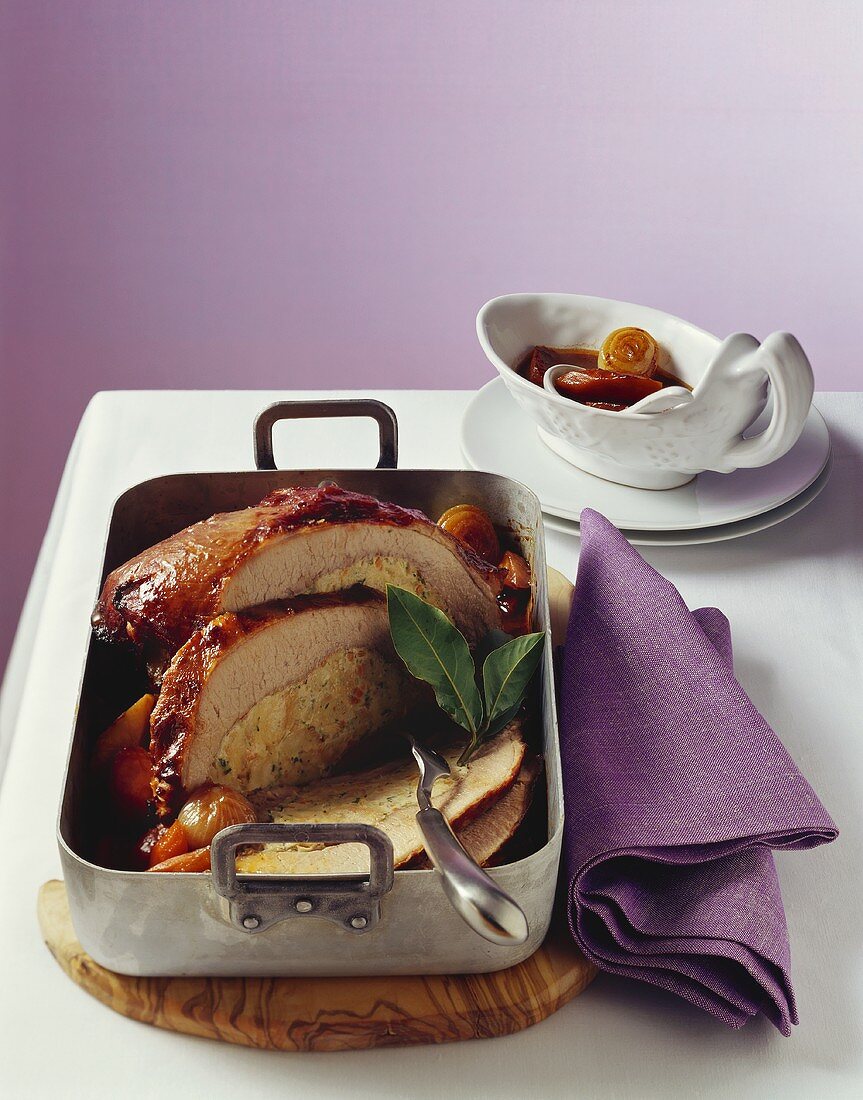 Stuffed veal breast with braised vegetables in roasting tin