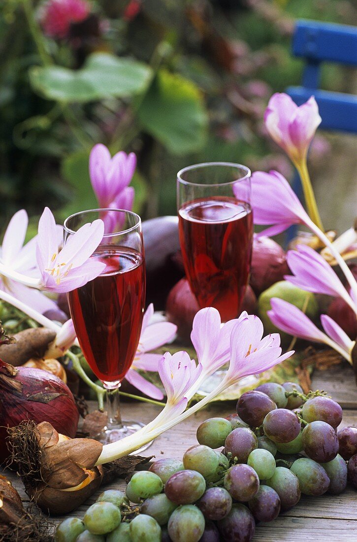 Autumn crocuses, grapes, red grape juice on table