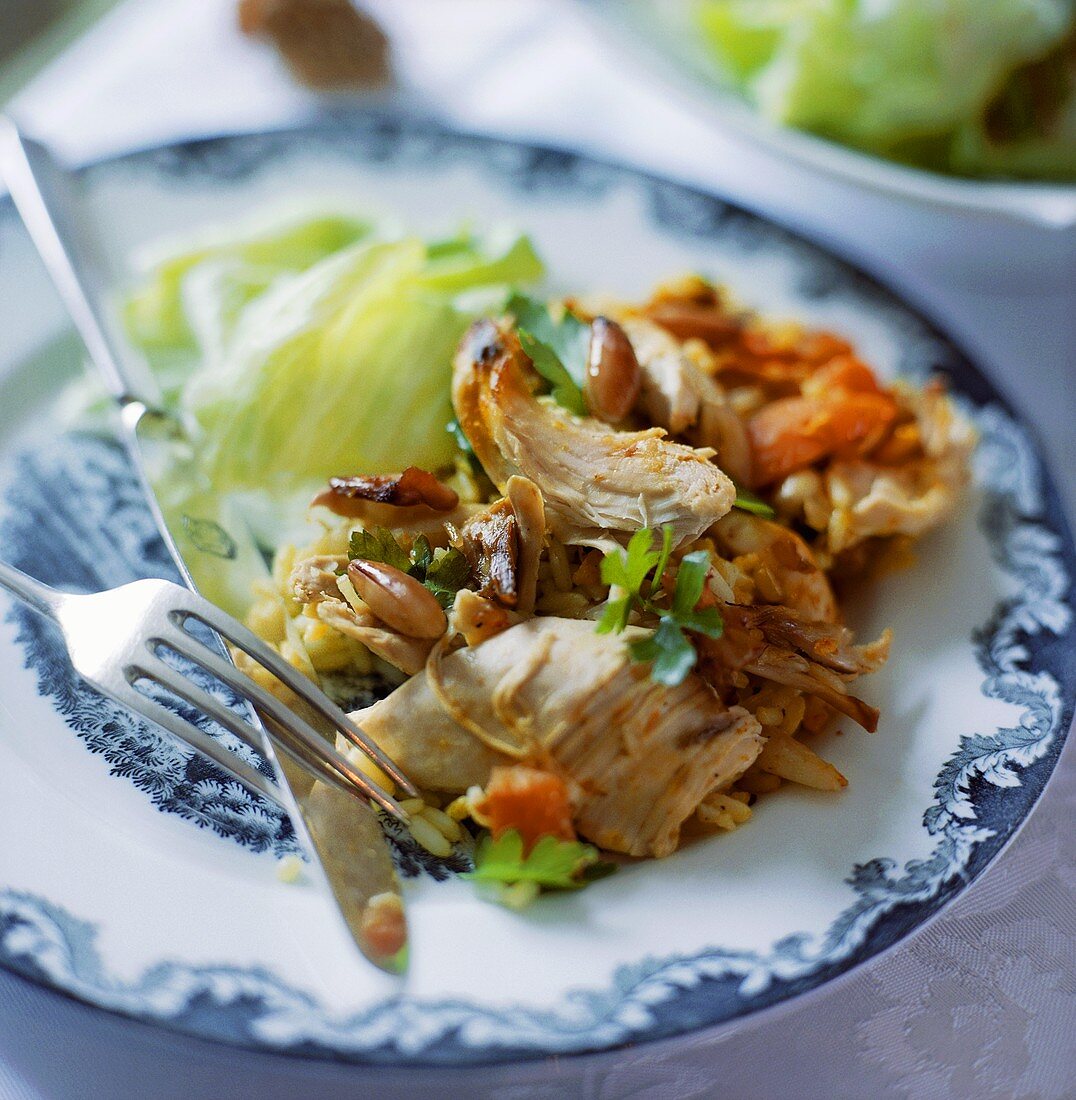Reisauflauf mit Hähnchenbrust und Nüssen auf Teller mit Salat