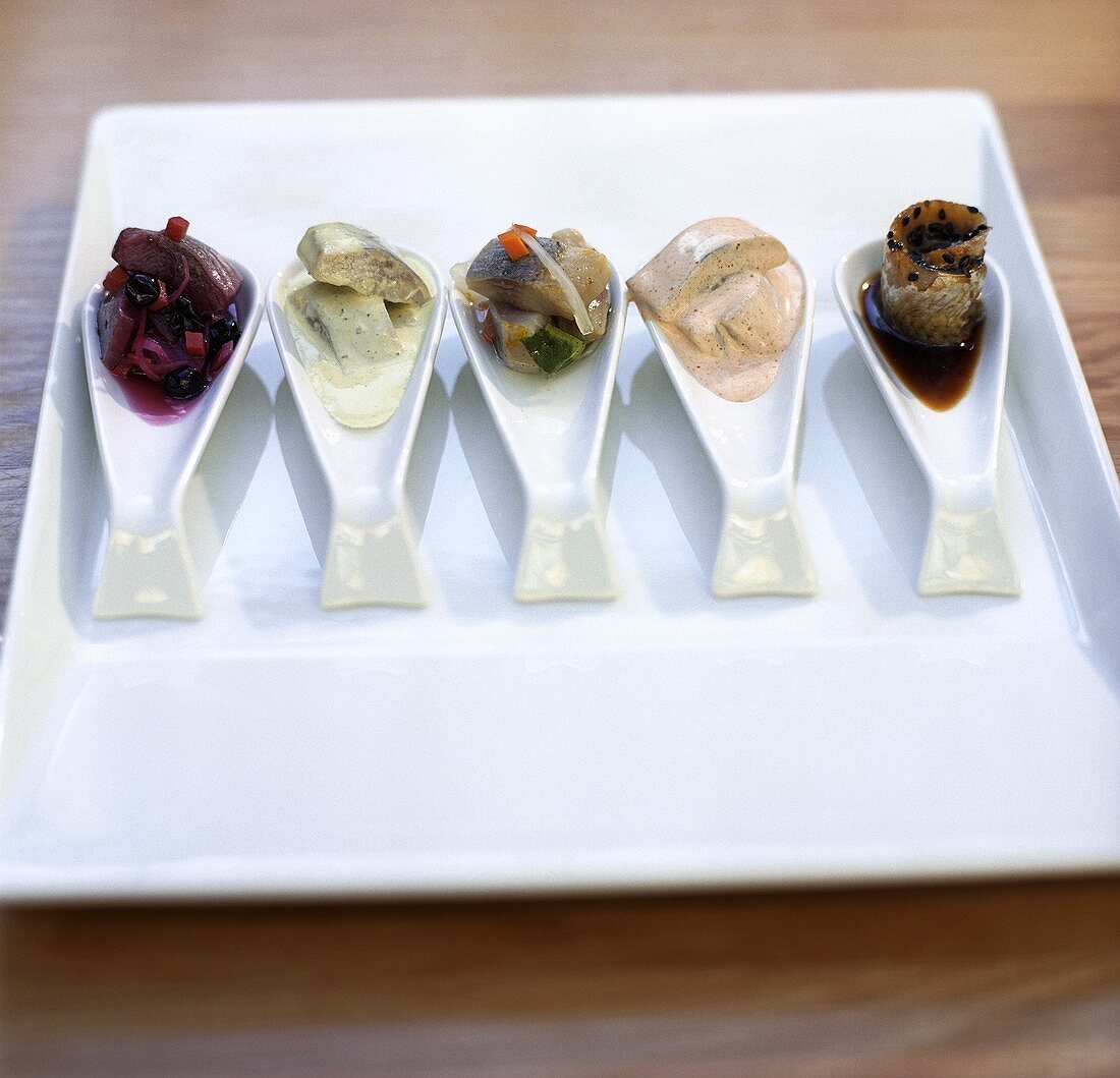 Assorted herring appetisers on spoons