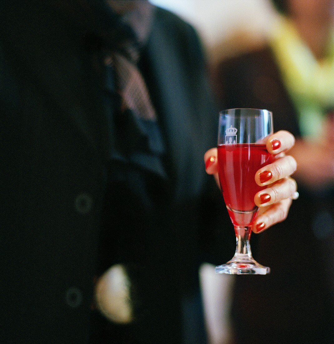 Woman's hand holding a glass of Kir Royal