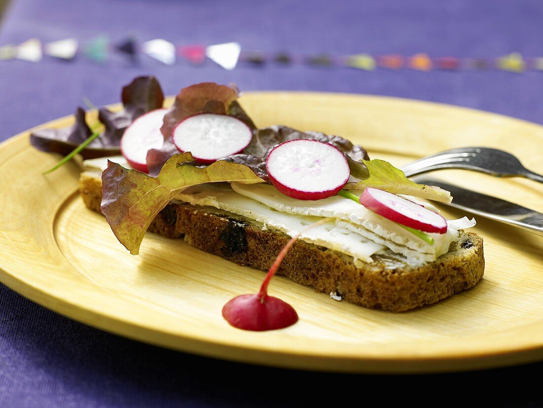 A slice of Swedish långpannebröd topped with cheese and radishes