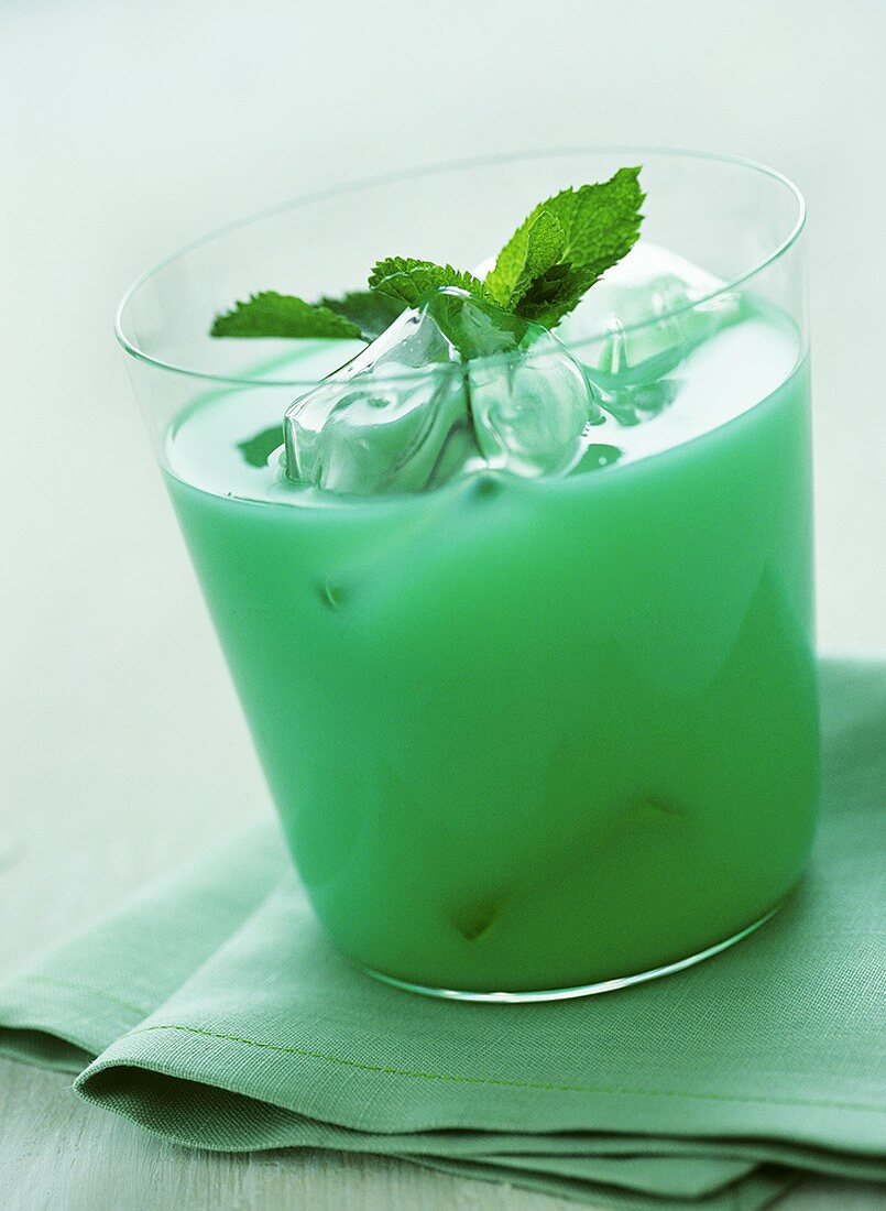 Grüner Cocktail mit Eiswürfeln und Minzblättchen