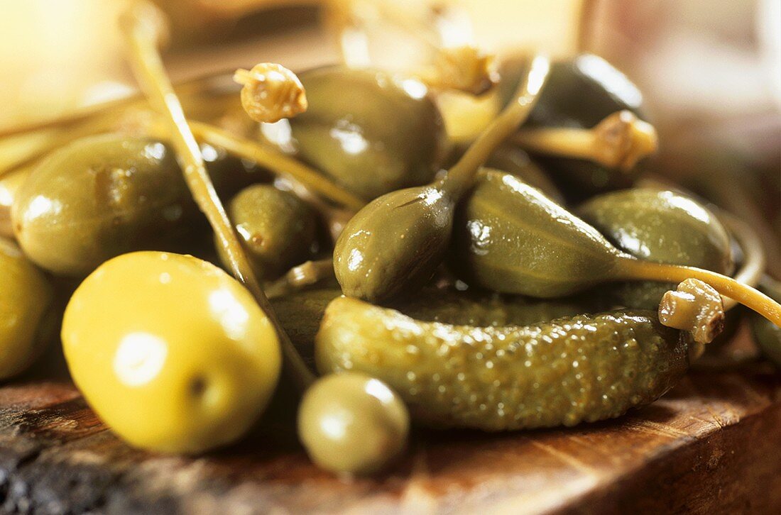 Capers, green olives and gherkins on a kitchen board