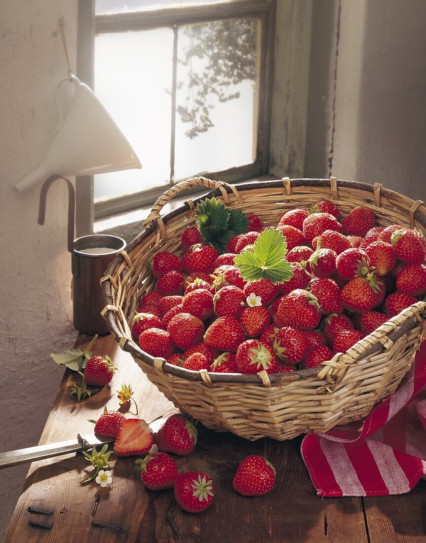 A basket of strawberries in front of a window