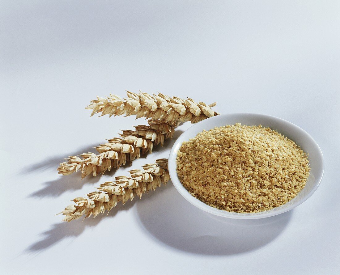 Three ears of wheat and wheatgerm in a small bowl