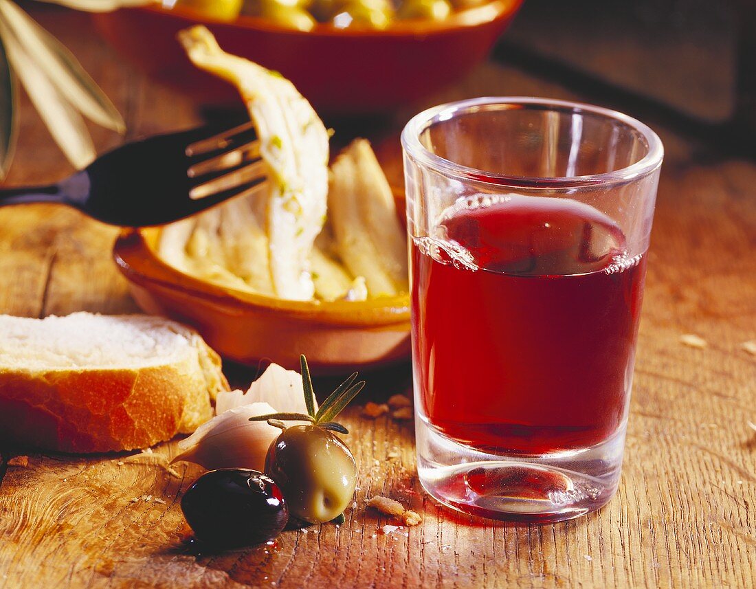 Stillleben mit Rotweinglas, Oliven und Anchovis